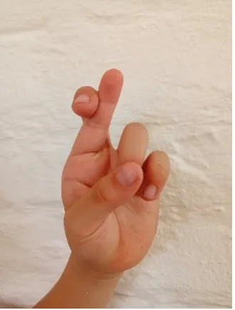 A child's hand forms the letter 'R' in Colombian Sign Language, expanding their sign language alphabet.