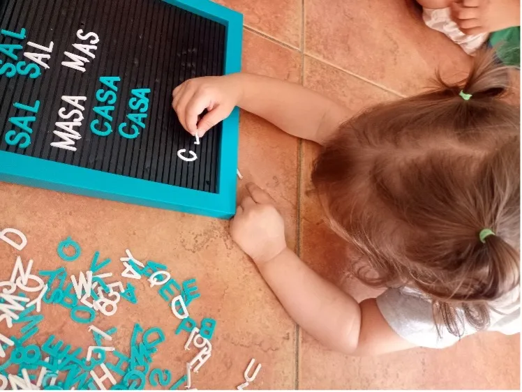 A child practices forming words on a letter board, developing early literacy skills.