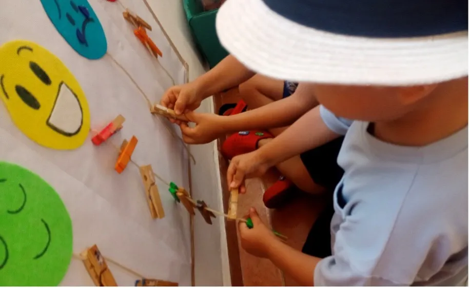 Children practice their fine motor skills by clipping clothespins onto a string, an activity that also encourages concentration and coordination.