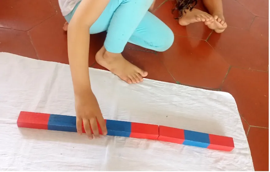 A child works with the Montessori Number Rods, a hands-on material for understanding quantity and learning to count.